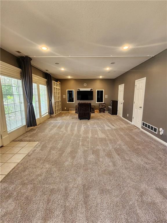 unfurnished living room featuring light carpet, baseboards, recessed lighting, and a textured ceiling