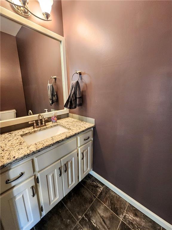 bathroom with vanity, baseboards, and marble look tile flooring