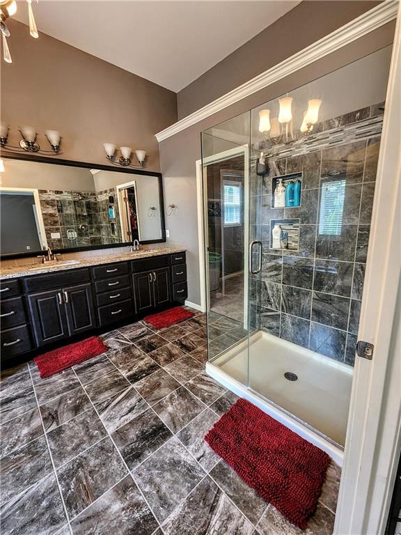 full bathroom with a shower stall, double vanity, and a chandelier