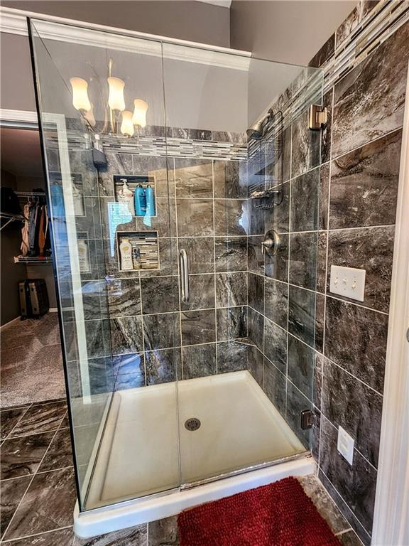 full bath with a stall shower and marble finish floors