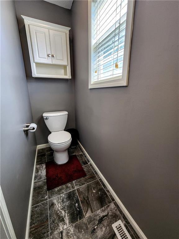 bathroom featuring baseboards, toilet, and marble look tiles