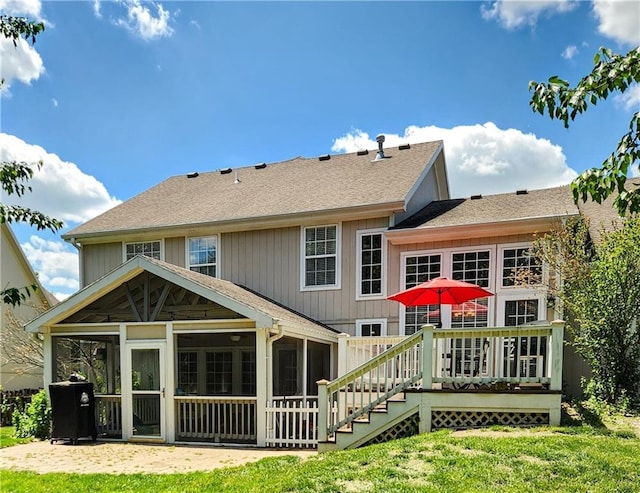 back of house with a sunroom, a wooden deck, a yard, and roof with shingles