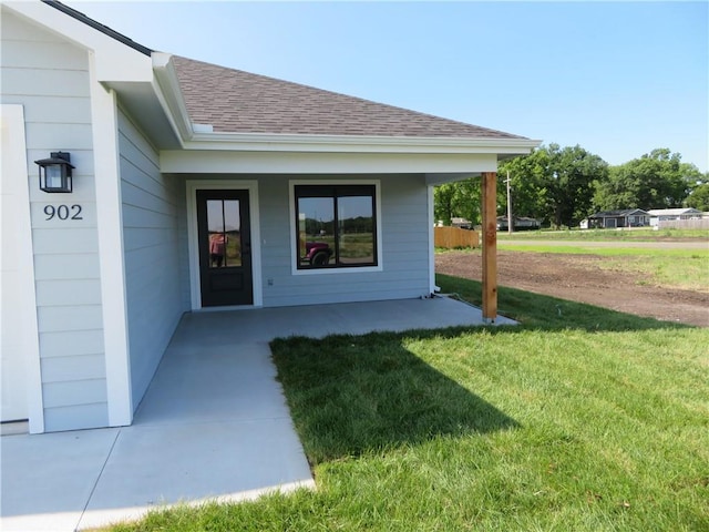 902 2nd St, Perry, KS 66073 - view of exterior entry featuring a lawn, a shingled roof, and covered porch
