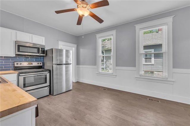 1010 N 13th St, Leavenworth, KS 66048 - kitchen featuring appliances with stainless steel finishes, wooden counters, a wainscoted wall, white cabinets, and light wood finished floors