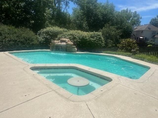 outdoor pool featuring an in-ground hot tub, fence, and a patio area
