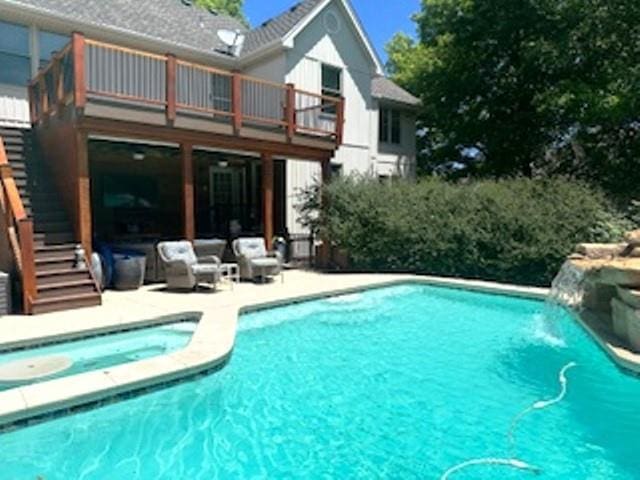 rear view of house featuring stairs, an in-ground hot tub, an outdoor pool, a patio, and a balcony