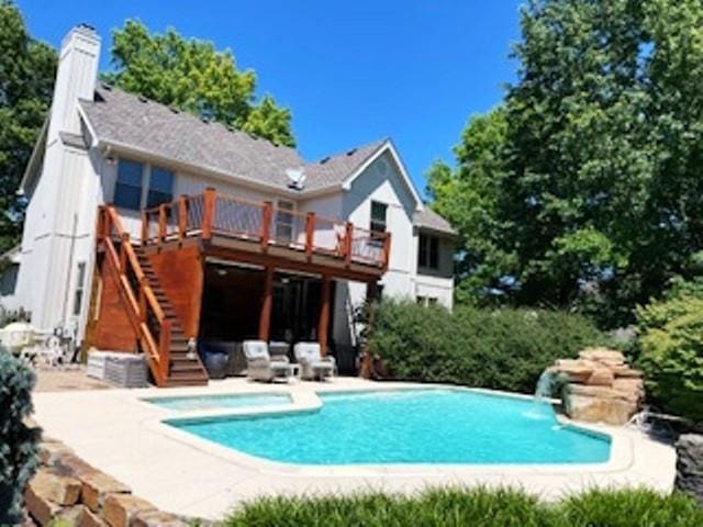 rear view of property with stairs, a deck, an outdoor pool, and a patio