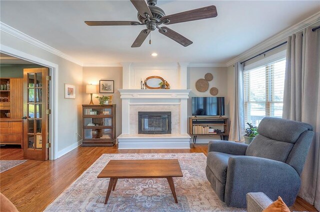 2007 NE Newport Ct, Blue Springs, MO 64014 - living room featuring crown molding, a tile fireplace, ceiling fan, wood finished floors, and baseboards