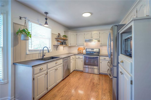 2007 NE Newport Ct, Blue Springs, MO 64014 - kitchen featuring appliances with stainless steel finishes, a sink, under cabinet range hood, light wood-style flooring, and open shelves