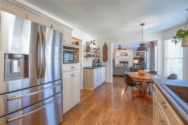 2007 NE Newport Ct, Blue Springs, MO 64014 - kitchen with stainless steel fridge, a fireplace, black microwave, ceiling fan, and light wood-style floors