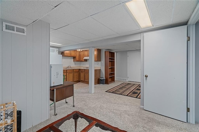 unfurnished living room with a paneled ceiling, a sink, and light carpet