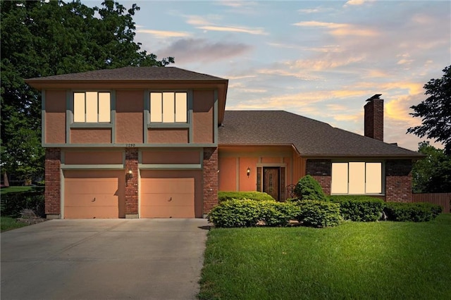 view of front of home featuring driveway, a front yard, a garage, a chimney, and brick siding