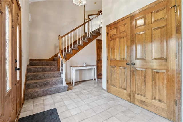 foyer entrance featuring stairs, a high ceiling, and light tile patterned flooring