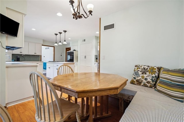 dining space with a chandelier, light wood-style floors, and recessed lighting