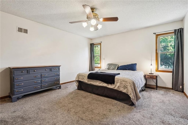 carpeted bedroom featuring multiple windows, baseboards, a textured ceiling, and ceiling fan