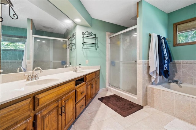bathroom with a stall shower, double vanity, tile patterned floors, and tiled bath
