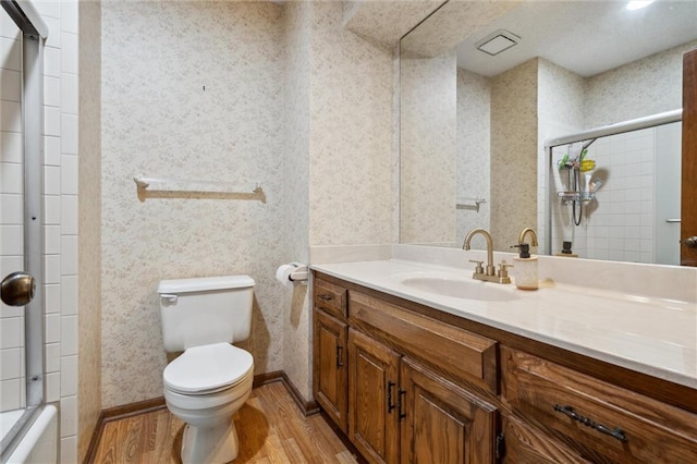 bathroom featuring wallpapered walls, wood finished floors, toilet, vanity, and baseboards