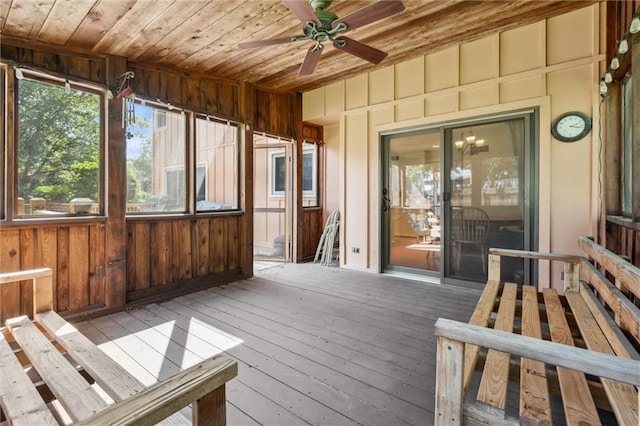 unfurnished sunroom featuring wooden ceiling, ceiling fan, hardwood / wood-style flooring, a deck, and wooden walls