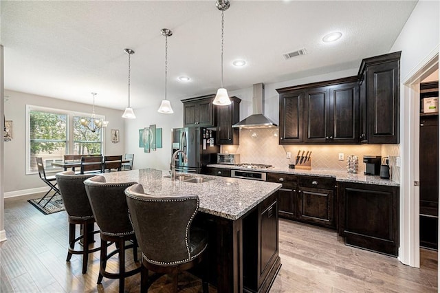 4310 N 141st Pl, Basehor, KS 66007 - kitchen featuring wall chimney exhaust hood, stainless steel fridge, a sink, light wood-type flooring, and a breakfast bar area