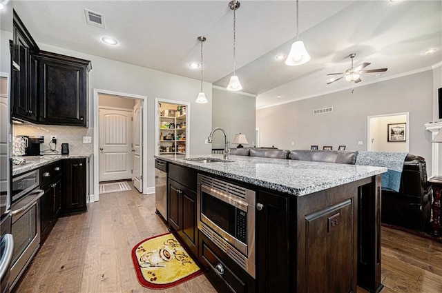 4310 N 141st Pl, Basehor, KS 66007 - kitchen featuring appliances with stainless steel finishes, a sink, crown molding, open floor plan, and wood finished floors