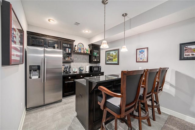 4310 N 141st Pl, Basehor, KS 66007 - kitchen featuring stainless steel refrigerator with ice dispenser, a breakfast bar, baseboards, black microwave, and backsplash