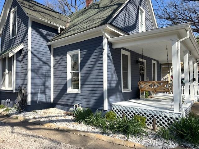 view of side of home featuring a porch and a chimney