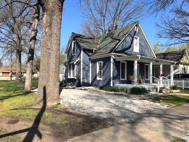 view of side of home with a porch and a chimney