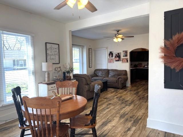 dining room with a ceiling fan, wood finished floors, baseboards, and arched walkways