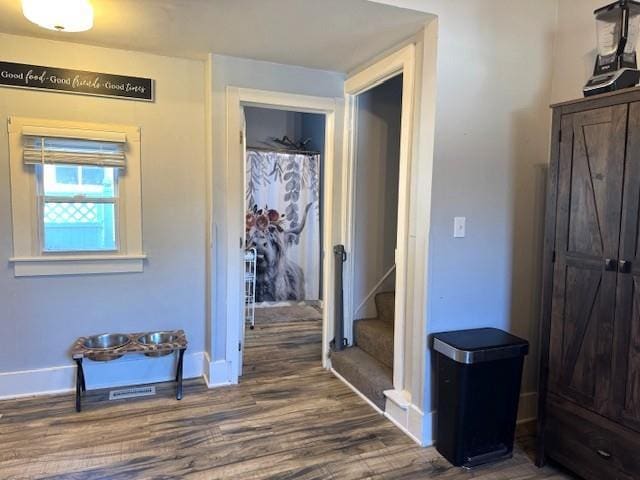 hallway with baseboards, wood finished floors, and stairway