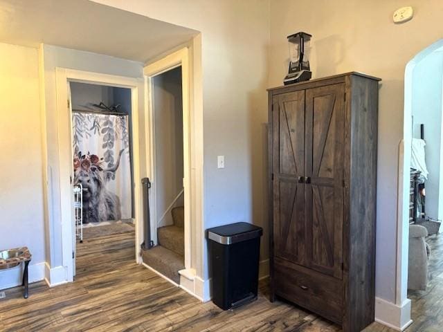 hallway featuring wood finished floors, stairway, arched walkways, and baseboards