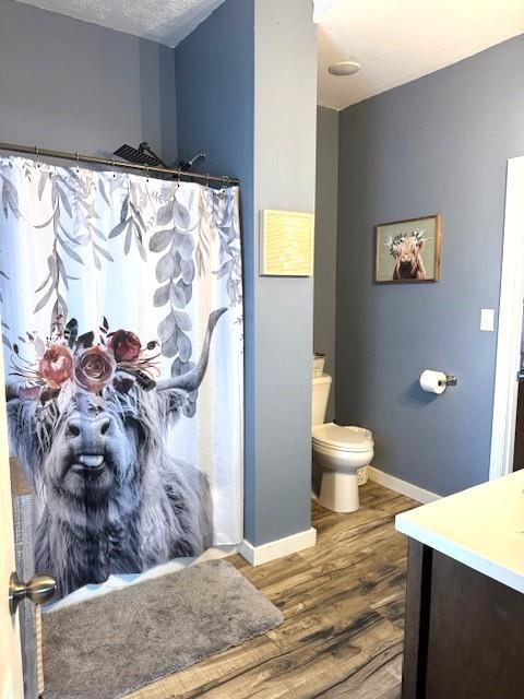 full bath featuring wood finished floors, baseboards, toilet, vanity, and curtained shower