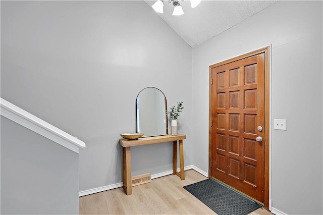 entryway with vaulted ceiling, wood finished floors, baseboards, and ceiling fan