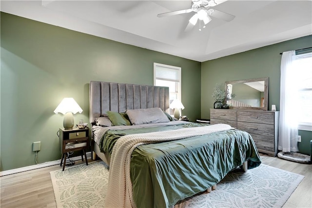 bedroom with light wood finished floors, baseboards, and ceiling fan