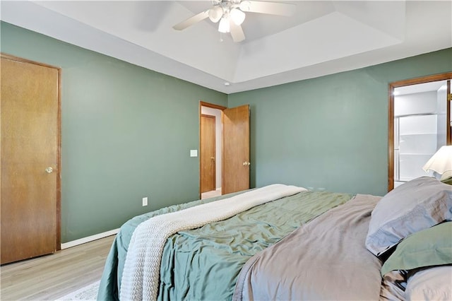 bedroom with a raised ceiling, wood finished floors, ceiling fan, and baseboards