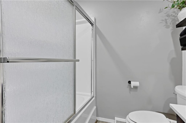 bathroom with toilet, baseboards, vanity, and shower / bath combination with glass door