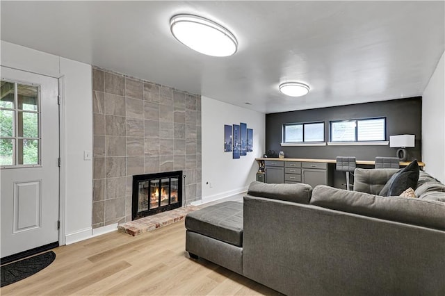 living room featuring light wood-style floors, baseboards, and a fireplace