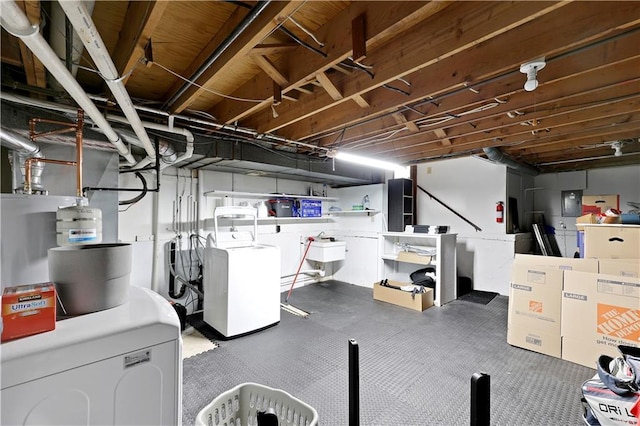unfinished below grade area with washer / clothes dryer and a sink