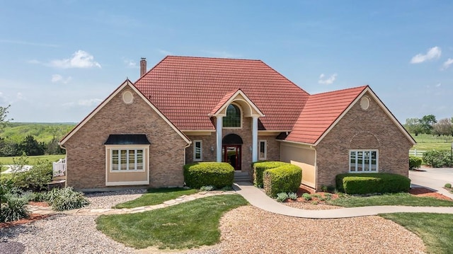 view of front of home with a tile roof, a chimney, and brick siding