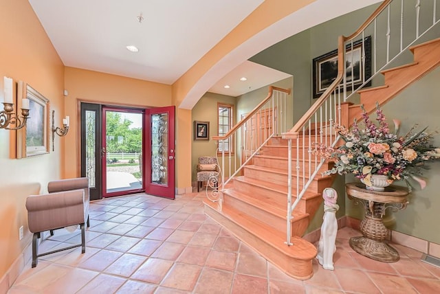 tiled entryway featuring arched walkways, stairs, recessed lighting, and baseboards
