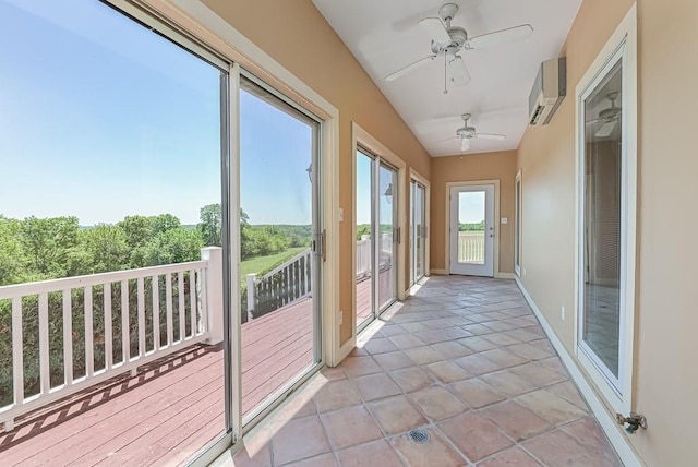 unfurnished sunroom featuring an AC wall unit, tile patterned flooring, and baseboards