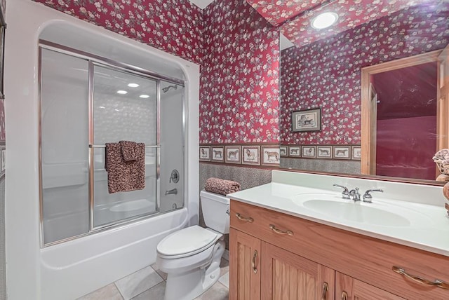 full bath with wallpapered walls, vanity, toilet, wainscoting, and bath / shower combo with glass door