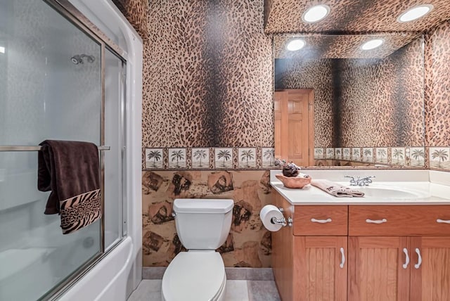 full bath featuring toilet, vanity, and bath / shower combo with glass door