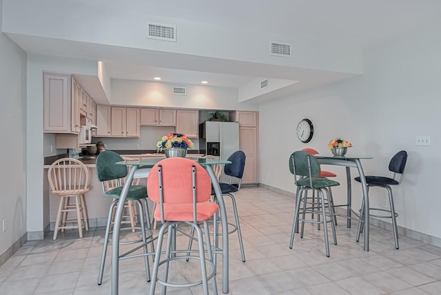 kitchen with dark countertops, stainless steel fridge with ice dispenser, a peninsula, baseboards, and recessed lighting