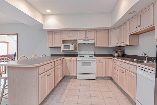 kitchen with white appliances, a sink, under cabinet range hood, a peninsula, and light tile patterned floors