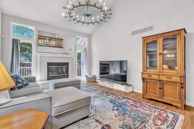 11065 W 98th St, Overland Park, KS 66214 - living area featuring a chandelier, high vaulted ceiling, wood finished floors, and a tile fireplace