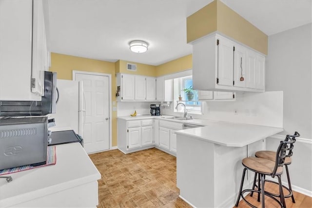 11065 W 98th St, Overland Park, KS 66214 - kitchen featuring a peninsula, white cabinets, a breakfast bar, and light countertops
