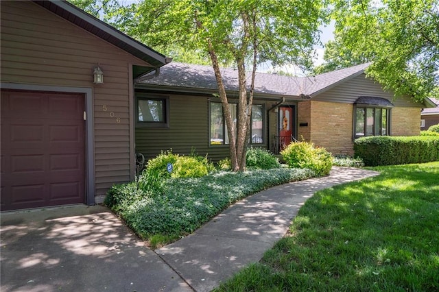 view of front of house featuring a garage, a front yard, driveway, and brick siding