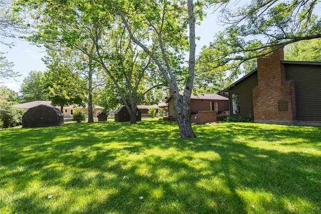 view of green lawn featuring a storage unit and an outbuilding
