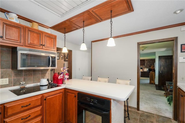 kitchen featuring black appliances, a peninsula, light countertops, and decorative light fixtures
