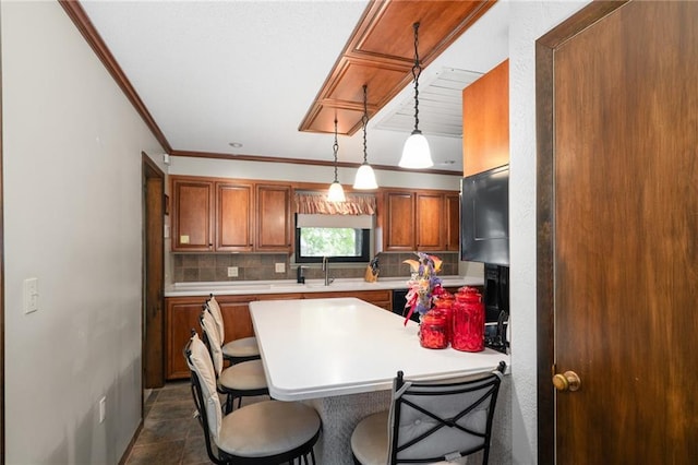 kitchen featuring a kitchen breakfast bar, light countertops, tasteful backsplash, crown molding, and brown cabinets